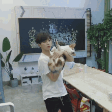 a man is holding a dog in front of a chalkboard with the word hi on it