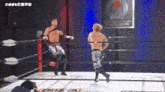two men are wrestling in a ring with a sign that says london in the background