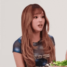 a woman with long hair is holding a bowl of salad .