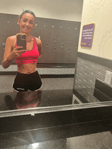a woman is taking a picture of herself in a gym mirror