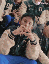 a boy wearing a green jacket with the letter d on it