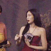 a woman in a red dress is holding a card in her hand
