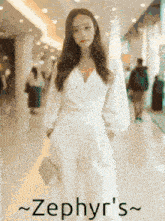 a woman in a white jumpsuit is standing in a hallway with the name zephyr 's written on the bottom