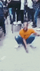 a man is squatting down in front of a crowd of people .