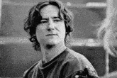 a black and white photo of a young man with long curly hair .