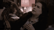 a woman is laying on a bed with her arm outstretched and a tv screen behind her that says abc