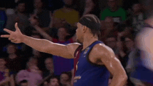 a basketball player wearing a blue jersey with the number 1 on it stands in front of a crowd .