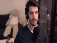a man wearing headphones is talking into a microphone in front of a teddy bear .