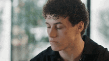 a young man with curly hair and a tattoo on his forehead