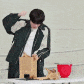 a man in a black jacket is holding a cardboard box