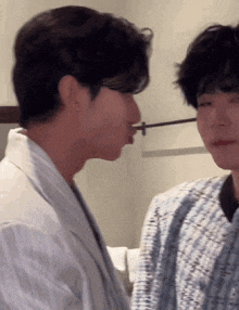 a couple of men are standing next to each other and one of them is holding a toothbrush in his mouth .