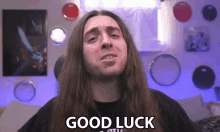 a man with long hair says good luck in front of drums