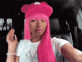 a woman with pink hair and a pink hat is sitting in a car .