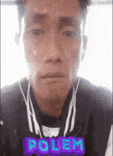a man wearing ear buds and a polem sticker on his shirt