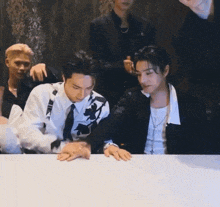 a group of men are sitting at a table .