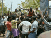 a man in an orange tank top is being lifted in the air by a crowd