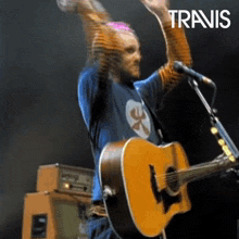 a man playing a guitar and singing into a microphone with the word travis on the bottom