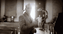 a black and white photo of a man in a suit standing in a church