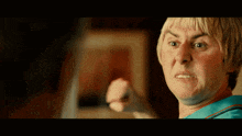 a man with blonde hair and a blue shirt is pointing