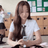 a girl in a white shirt and tie looks at her phone