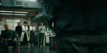 a group of people are standing in a room watching a man throw a lightning bolt .