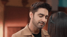 a man with a beard is looking at a woman with her eyes closed .