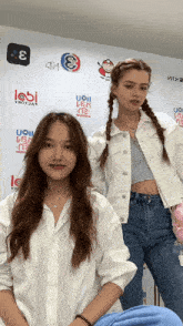 two girls are standing in front of a wall with logos for uoii and labi
