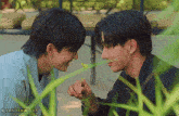 two young men are looking at each other and one of them is holding a flower ..