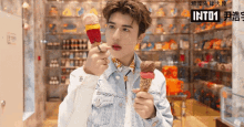 a man holding two ice cream cones in front of a sign that says into