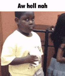 a young boy is holding a cup and making a funny face with the words aw hell nah above him .