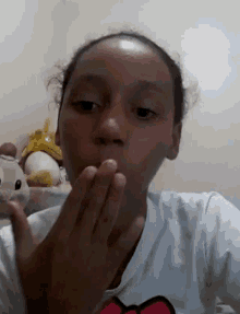 a young girl is making a funny face with her hands in front of her face .