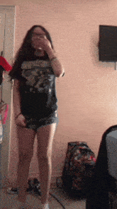 a girl wearing shorts and a black shirt is standing in a room