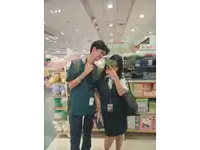 a man and a woman are taking a picture in front of a sign that says ' happy birthday '
