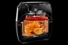 a chicken is cooking in an air fryer with red arrows pointing to it