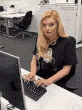 a woman in a black t-shirt is typing on a keyboard