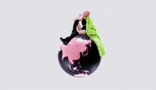 a woman in a green fur coat sits on a pink surface