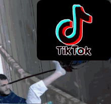 a man is hanging from a rope with a tiktok logo behind him