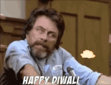 a man with a beard is sitting in front of a microphone and saying happy diwali .