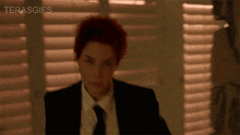 a woman with red hair is wearing a suit and tie .