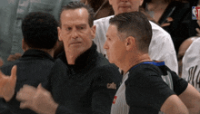 a man wearing a jacket that says cavs talks to another man