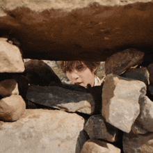 a person looking through a hole in a wall of rocks