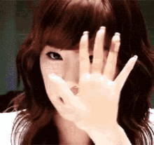 a woman covering her face with her hand while looking at the camera