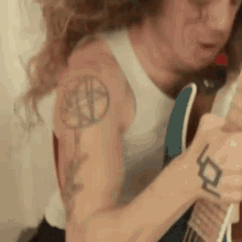 a man with a tattoo on his arm is playing a guitar
