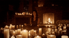 a woman sits in a lotus position in front of a fireplace surrounded by candles