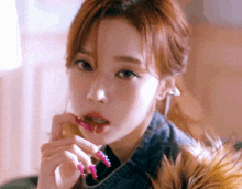 a close up of a woman with long pink nails and a denim jacket
