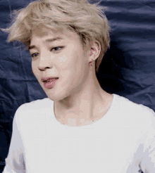 a close up of a person with blonde hair wearing a white shirt and earrings .
