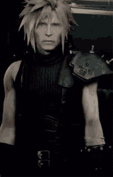 a man with blonde hair is wearing a black tank top and a black armor .