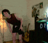a man wearing headphones is standing in a room with a guitar and a chair with the number 00 on the back