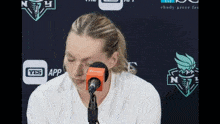 a woman is sitting in front of a microphone with a yes app icon in the background