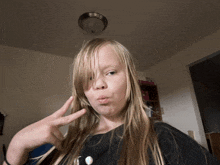 a young girl making a peace sign with her finger